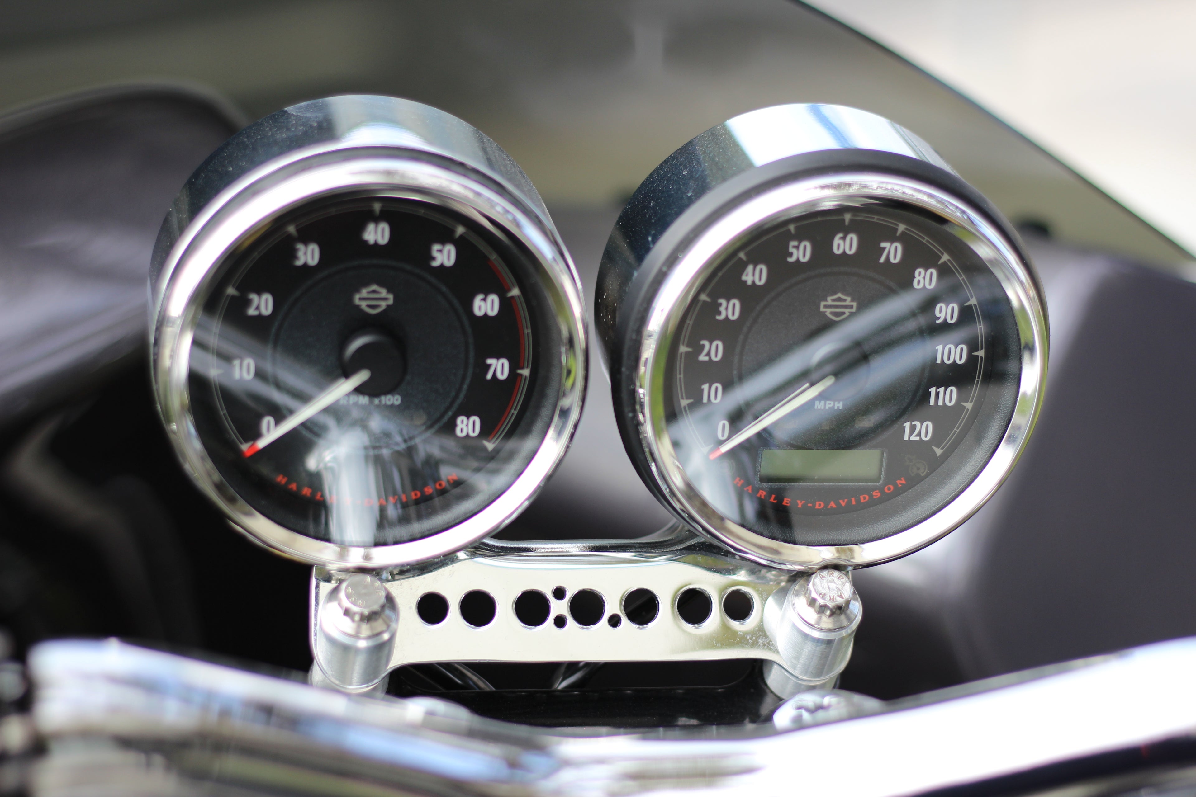 Dual gauge relocation kit mounted on Harley Dyna T-bars with speedometer and tachometer