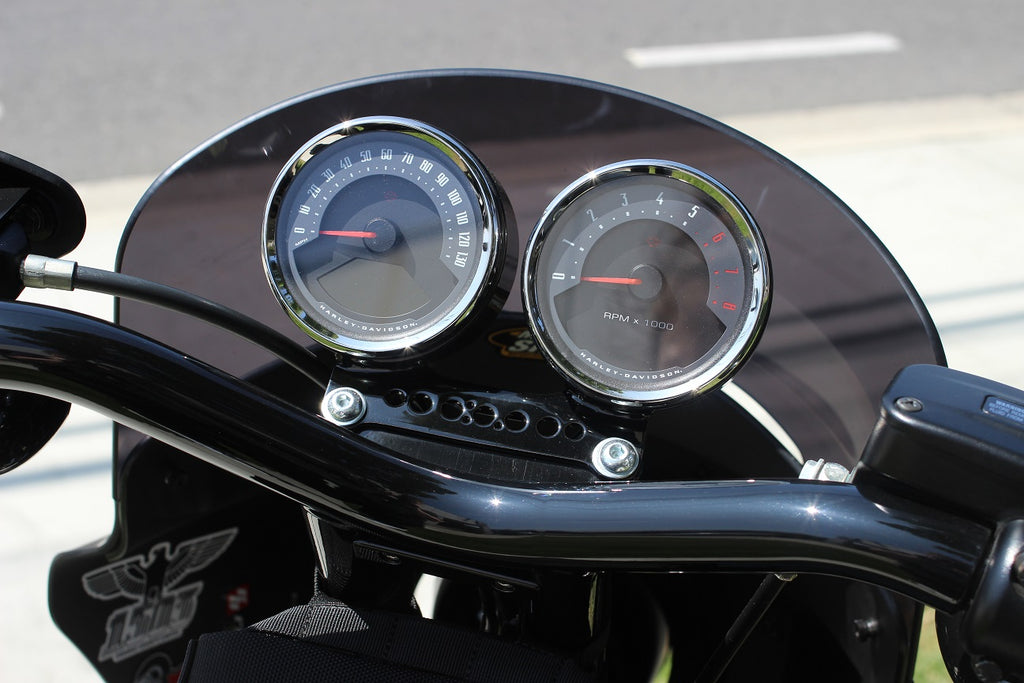 Dual gauge relocation kit mounted on Harley Dyna T-bars with speedometer and tachometer