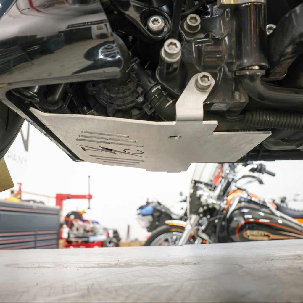 Skid plate protecting exposed water line and wiring on Harley Road Glide